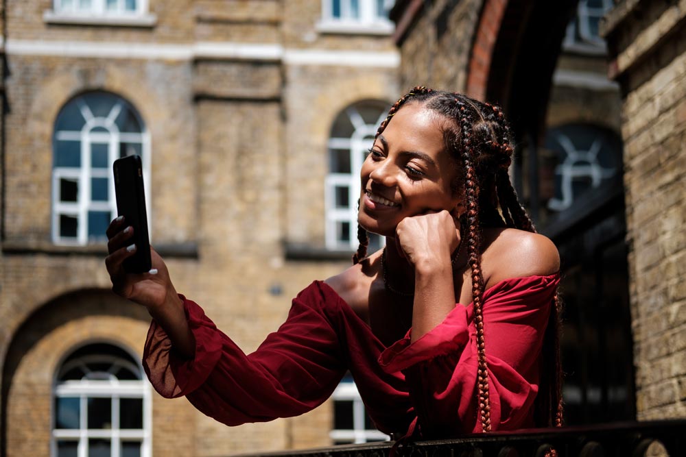 A phd candidate using social media on her phone in a courtyard